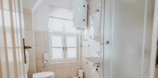 Small tiled bathroom with toilet, sink, and shower