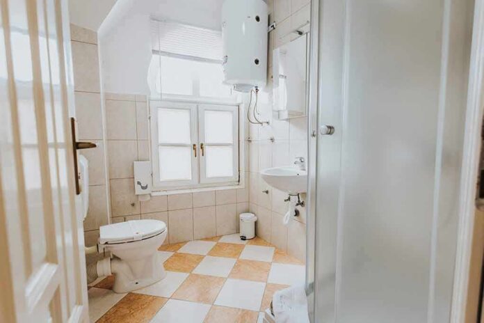Small tiled bathroom with toilet, sink, and shower