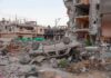 Overturned car amid rubble and heavily damaged buildings