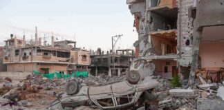 Overturned car amid rubble and heavily damaged buildings
