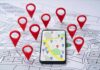 Smartphone with map app surrounded by red location pins