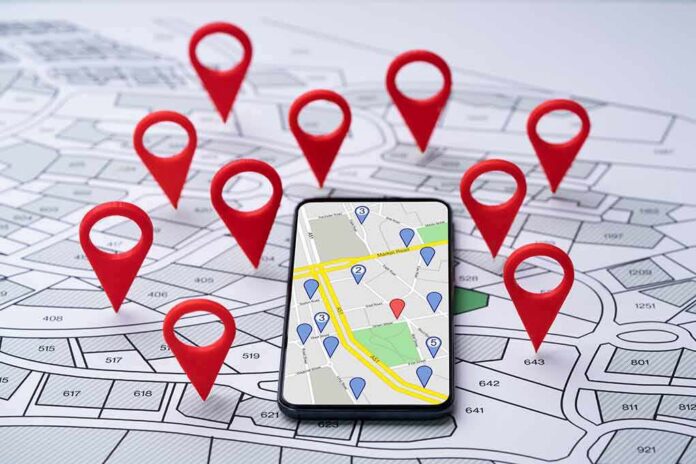 shutterstock_2151128813 Smartphone with map app surrounded by red location pins
