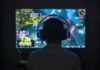 Gamer wearing headphones facing a large screen