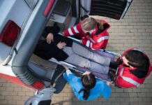 Paramedics load a patient on a stretcher into an ambulance