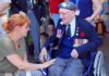 Elderly veteran in wheelchair greeted by woman