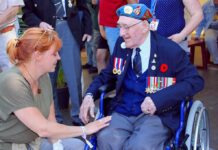 Elderly veteran in wheelchair greeted by woman