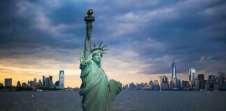 Statue of Liberty with city skyline at dusk