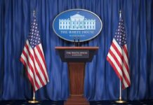 White House press podium with microphones and two American flags