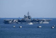 Aircraft carrier at sea with small boat alongside