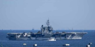 Aircraft carrier at sea with small boat alongside