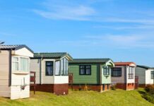 Row of colorful mobile homes on a grassy hill under a blue sky