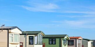 Row of colorful mobile homes on a grassy hill under a blue sky