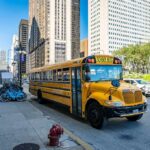 BMW CRASH Chaos: Kids Hospitalized! Yellow school bus on a city street beside skyscrapers
