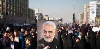 Qasem Soleimani portrait held aloft in a crowded street gathering