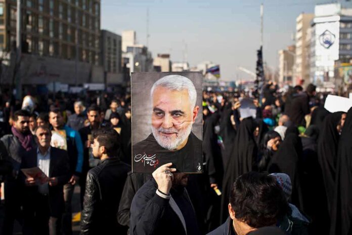 Qasem Soleimani portrait held aloft in a crowded street gathering