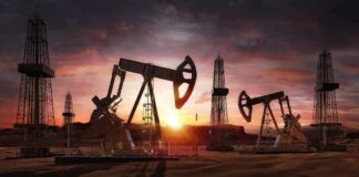 Oil pumpjacks and derricks at sunset in a desert field