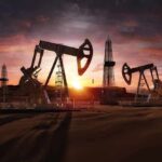 Oil pumpjacks and derricks at sunset in a desert field