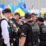 Police officers stand among a crowd with blue and yellow flags