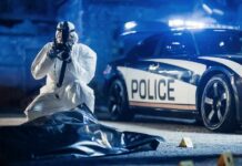 Star Athlete Stabbed After Midnight Clash forensic investigator photographing crime scene near police car