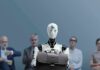 Jan-Peter Nikiferow seated with a humanoid robot holding a briefcase in front