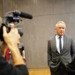 Robert F. Kennedy Jr. speaks with a reporter while being filmed indoors