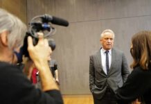Robert F. Kennedy Jr. speaks with a reporter while being filmed indoors