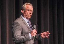 man in a suit speaking into a microphone on stage