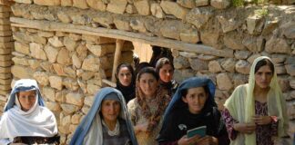 Group of women in traditional clothing standing in front of a stone wall