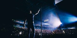 Singer on stage facing a large concert crowd