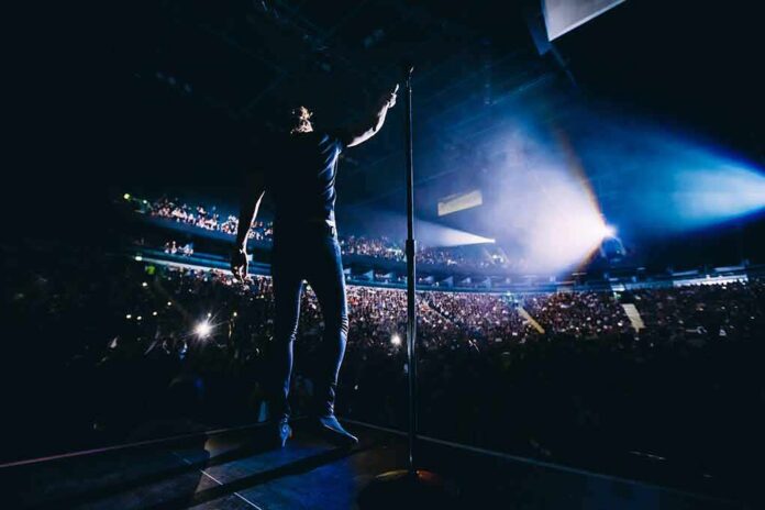 Singer on stage facing a large concert crowd