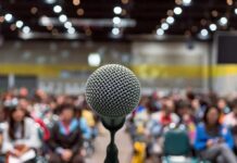 Microphone on stage facing a blurred audience