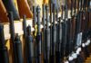 Shotguns and rifles lined up on a rack in a gun store