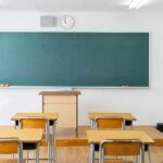 Empty classroom with desks facing a large chalkboard