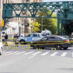 Police cars block a city intersection with yellow crime scene tape