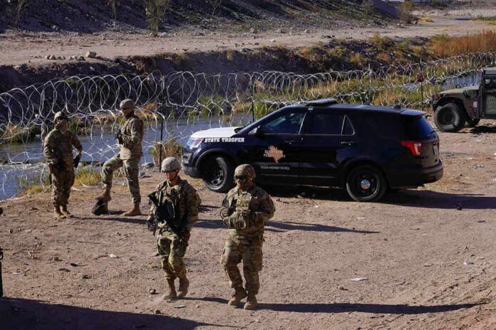 Soldiers stand near barbed wire beside a police SUV